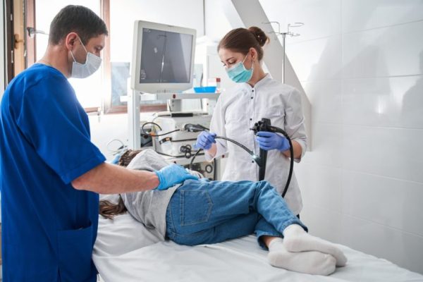 Female-doctor-holding-endoscope-while-making-gastroscopy-for-the-little-girl-768x512