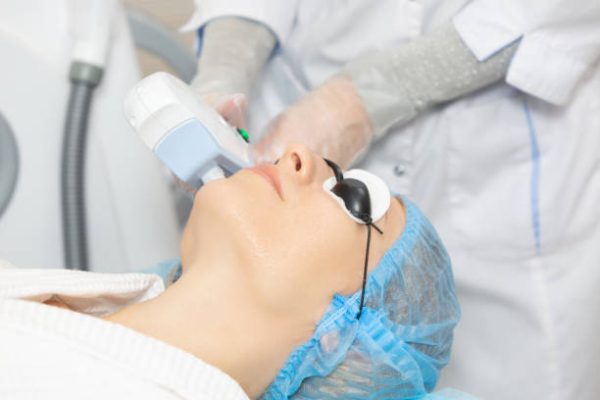 Woman client in a beauty salon is undergoing a photo rejuvenation procedure of alignment skin tone, removing traces of pigmentation. Starting the rejuvenation process by producing own collagen.